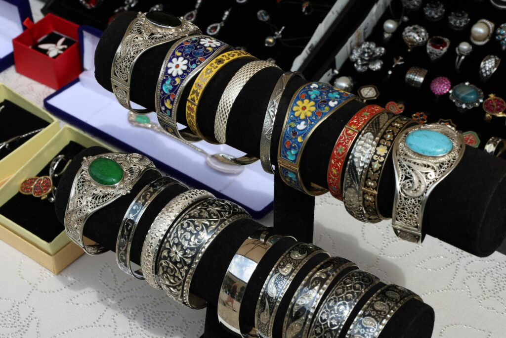 Colorful and intricate silver bracelets on display at a jewelry market stall, showcasing craftsmanship.