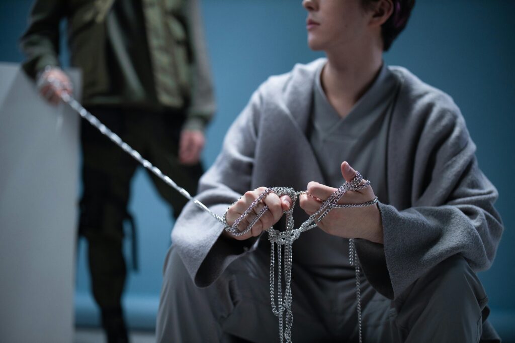Contemplative scene with two people holding chains, artistic setting.