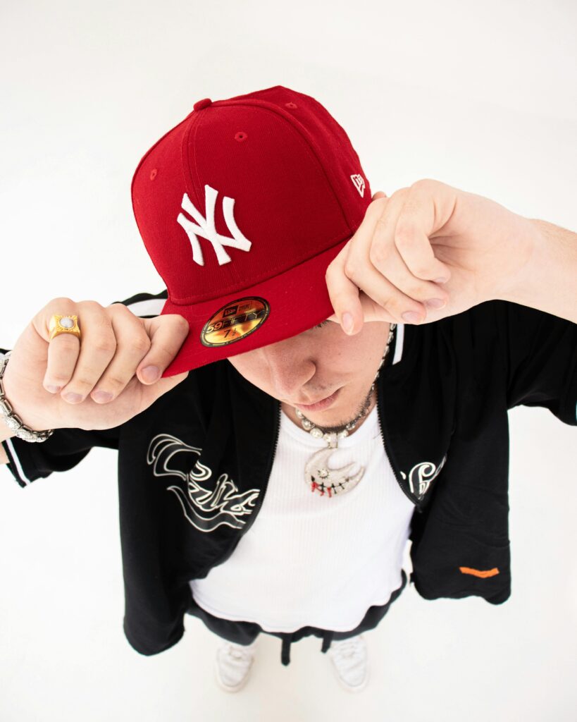 A fashionable adult wearing a red cap and black outfit, posing confidently.