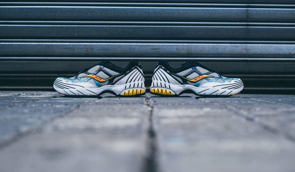 Close-up of stylish athletic sneakers placed on urban pavement against a metal backdrop.